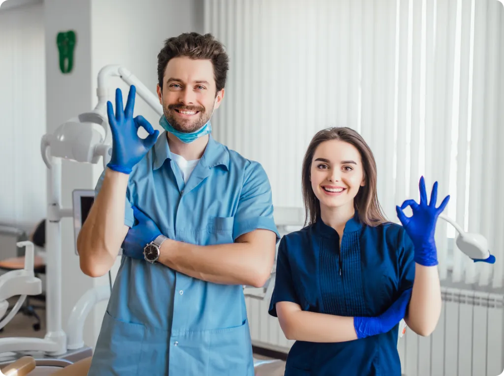 Smiling dentist and dental assistant in a treatment room